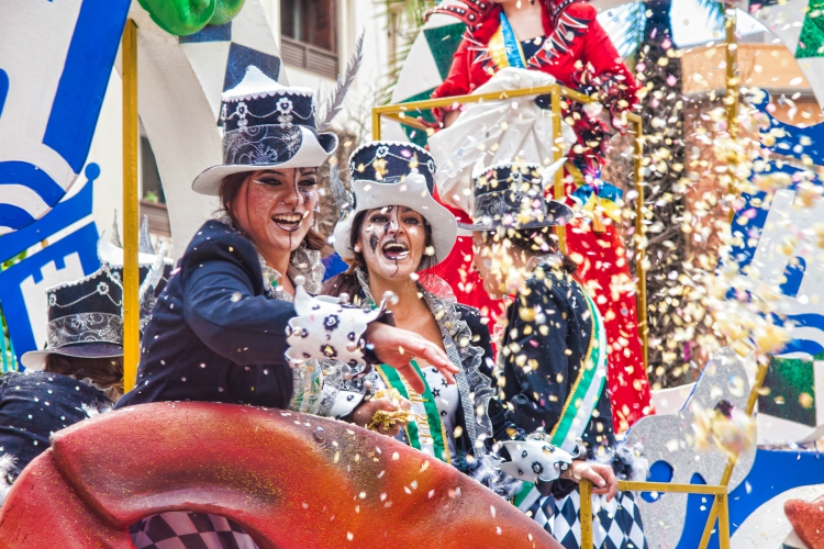 things to do in andalusia | ALGECIRAS, SPAIN - MARCH 05, 2017: Cheerful laughing Carnival participants throw confetti during the parade of the carnival in the street in Algeciras, Cadiz, Andalusia