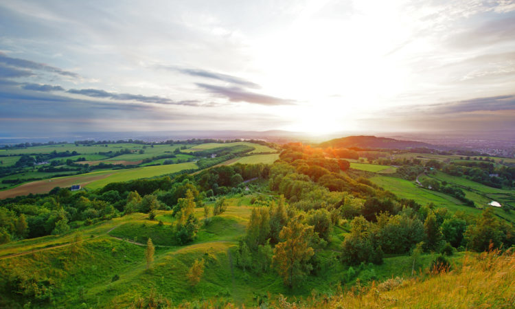 A beautiful sunset, with lens flare, in summer looking towards the Royal Forest of Dean from Painswick Beacon. This is a very popular viewing point in the Cotswolds, Gloucestershire, UK