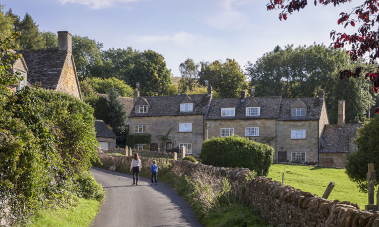 Mother and son walking dog in Cotswold village of Snowshill, England.