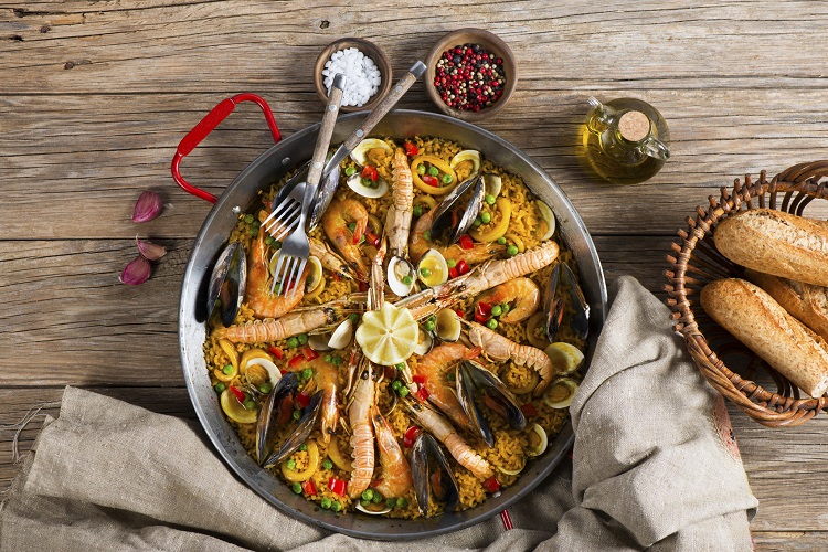 Top view of typical spanish seafood paella in traditional pan on a rustic wooden background