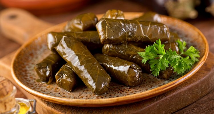 A plate of delicious stuffed grape leaves with parsley garnish.