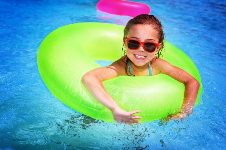 family activities in Umbria | Portrait of cute happy little girl having fun in swimming pool, floating in blue refreshing water with big green rubber ring, active summer vacation on the beach