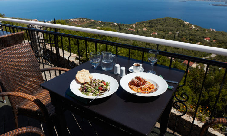 Pastitsada with bucatini pasta and vegetarian salad. Restaurant with a view over the ocean.