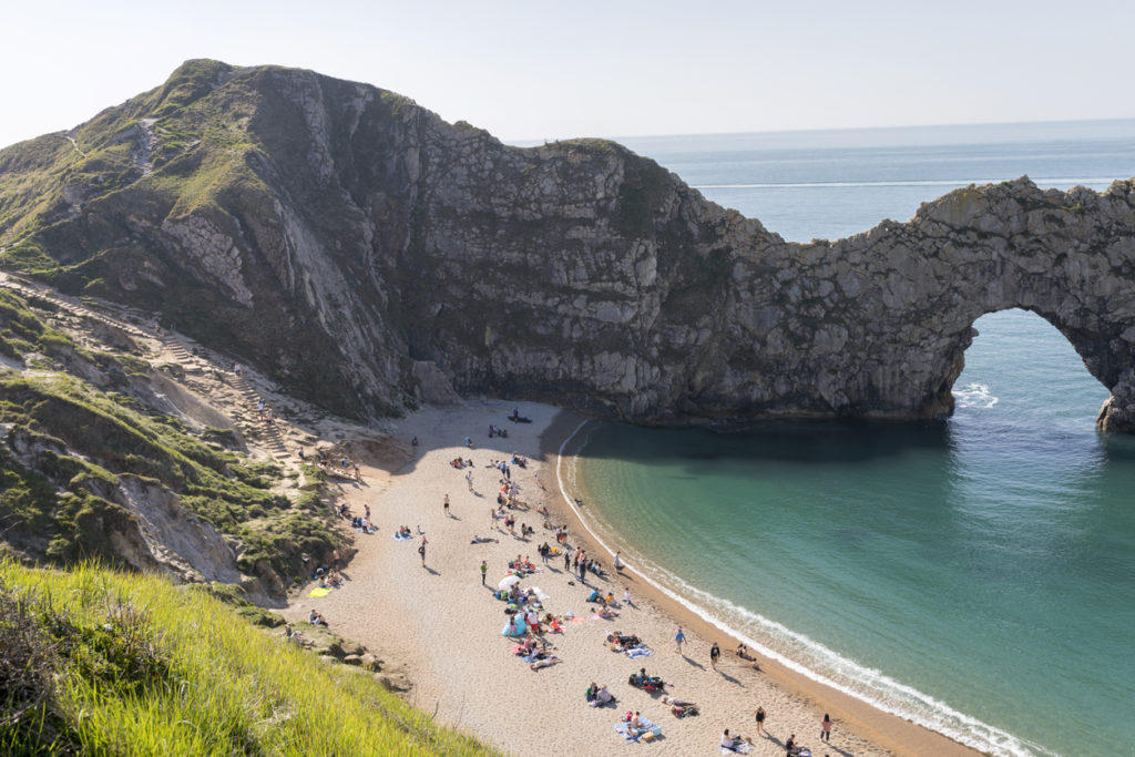 People rest and relax on the Durdle Door beach